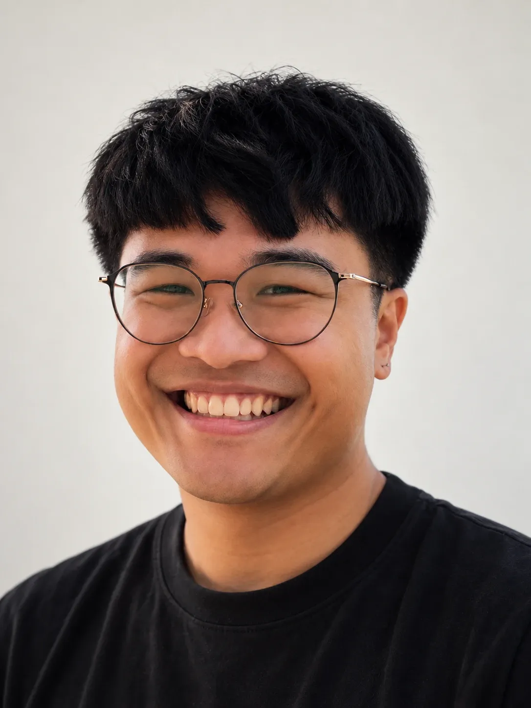 Portrait of Wilfredo, founder of LOOSHI LABO, smiling in round glasses and a black t-shirt.